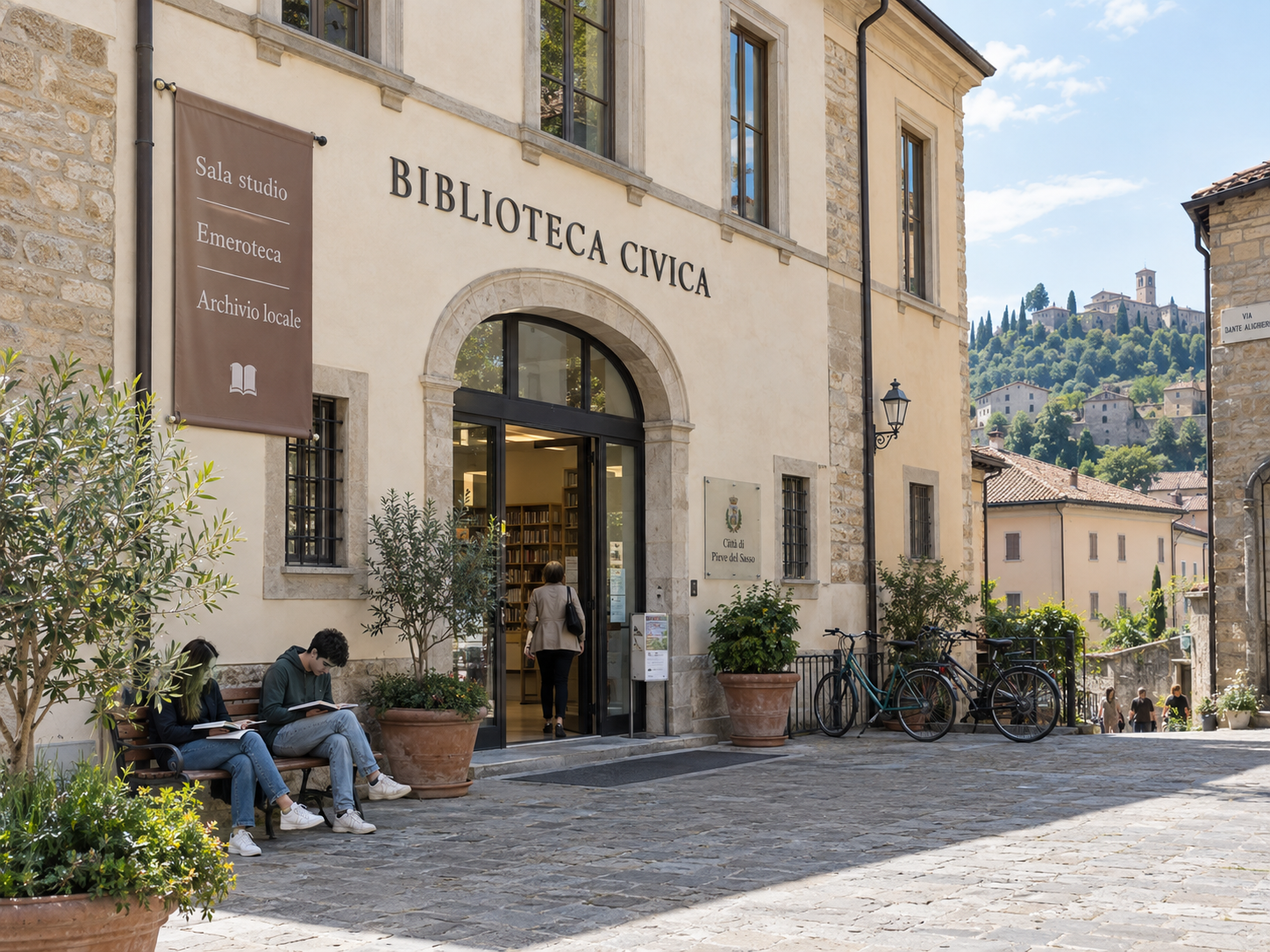 La facciata e l’ingresso della Biblioteca Civica, con lettori seduti all’esterno